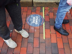 A marker for social distancing guideline is seen on the pavement outside of a tavern in the normally busy shopping district of Georgetown in Washington, DC on March 23, 2020. (Photo by MANDEL NGAN / AFP)