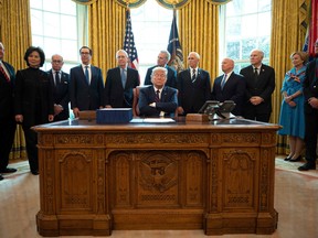US President Donald Trump signs the CARES act, a $2 trillion rescue package to provide economic relief amid the coronavirus outbreak, at the Oval Office of the White House on March 27, 2020.