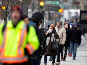 A woman adjusts her mask while she waits in line as the city's public health unit holds a walk-in clinic testing for COVID-19 in Montreal, Monday, March 23, 2020.
