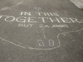 A message "in this together but 2m apart " is written on the driveway of a n Ajax home on Sunday, March 22, 2020. (Veronica Henri/Toronto Sun/Postmedia Network)