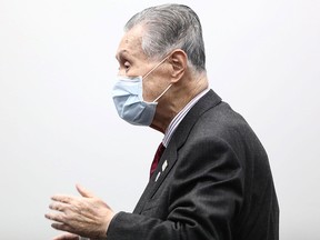 Tokyo 2020 president Yoshiro Mori puts on his face mask at the end of a press conference in Tokyo on March 30, 2020. -