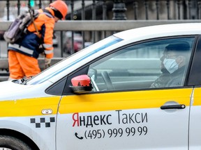 A taxi driver wearing a face mask drives his car in Moscow on March 23, 2020. (YURI KADOBNOV/AFP via Getty Images)
