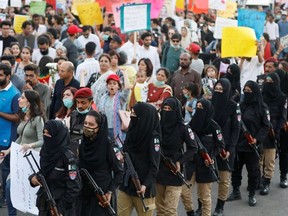 Female police officers escort women for a security measure as they attend the Aurat March (Women's March) in Karachi, Pakistan March 8, 2020.