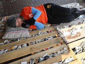Christine Sheppard feigns sleep on a pallet stuffed with newspaper outside University Centre on the University of Manitoba campus in Winnipeg on Sunday. Sheppard and four others will sleep outside for five nights to raise awareness and funds for homelessness. Kevin King/Winnipeg Sun/Postmedia Network