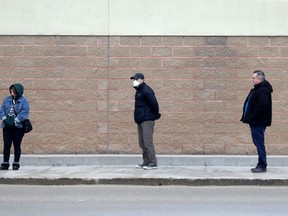 Customers keep their distance while in line waiting to enter an electronics store on St.James Street, in Winnipeg on Tuesday, March 24, 2020. Chris Procaylo/Winnipeg Sun