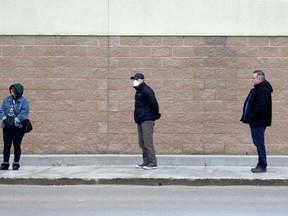 Customers keep their distance while in line waiting to enter an electronics store on St.James Street, in Winnipeg on Tuesday,  March 24, 2020. Chris Procaylo/Winnipeg Sun file