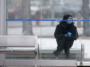 A person wears a mask and gloves while waiting in an otherwise empty bus shelter, on Broadway, in Winnipeg.   Tuesday, March 24/2020 Winnipeg Sun/Chris Procaylo/stf