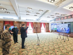 This photo released on March 10, 2020 by China's Xinhua News Agency shows Chinese President Xi Jinping wearing a mask as he waves to a coronavirus patient and medical staff via a video link at the Huoshenshan hospital in Wuhan, in China's central Hubei province on March 10, 2020.