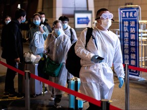 Passengers wear hazmat suit as they arrive at the Wuhan Wuchang Railway Station in Wuhan, to leave the city in China's central Hubei province early on April 8, 2020. (NOEL CELIS/AFP via Getty Images)