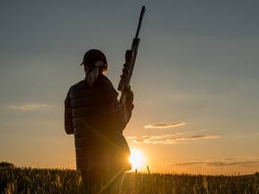A hunter in a field at sunset