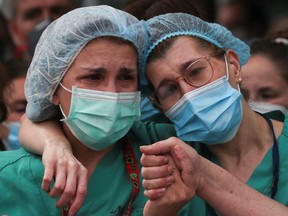 Health workers wearing protective face masks react during a tribute for their co-worker Esteban, a male nurse that died of the coronavirus disease, amid the COVID-19 outbreak, outside the Severo Ochoa Hospital in Leganes, Spain, Monday, April 13, 2020.
