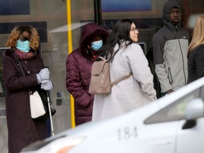 Health officials have confirmed community spread of COVID-19 in Winnipeg and are urging residents to stay at home.  This is a line up of customers waiting to enter a bank on Portage Avenue downtown on Wednesday, April 01, 2020. Chris Procaylo/Winnipeg Sun