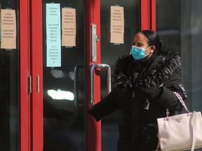 A woman wearing a mask reads Covid-19 related notices on the doors of Portage Place mall, in Winnipeg..  Saturday, April 04/2020 Winnipeg Sun/Chris Procaylo/stf