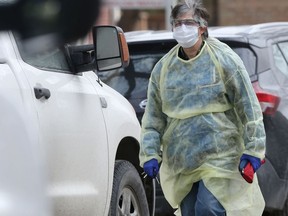 Person wearing a large amount of personal protective equipment walks along Stradbrook Avenue, in Winnipeg on Friday.