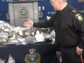 Screenshot off a Winnipeg Police Service Facebook Live press conference of Winnipeg Police Service Patrol Sgt. Jeffrey Norman of the Central Division Community Support Unit showing off items seized from an illegal cannabis trafficking operation in Winnipeg at a press conference at police headquarters on Friday. The business was known as ‘Dr Kush’ and was housed in a building located in the Sargent Park neighbourhood, which included a warehouse to assist in the distribution of cannabis. The operation had a website where customers could place online orders for cannabis. Drivers had been contracted to deliver the cannabis city-wide to customers. To conceal the deliveries, drivers used insulated bags labelled from commonly known restaurant delivery services. A 43-year-old male, of Winnipeg, will be charged with trafficking marijuana and possession of proceeds of crimes and over $200,000 of illegal cannabis, vaping oil and prepackaged shatter were seized.