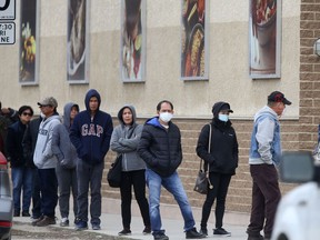 People line up outside a grocery store in Winnipeg on Saturday.