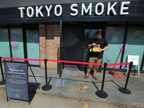 A Toyko Smoke cannabis shop employee looks into a box of chalk while marking the sidewalk in front of the Stradbrook Avenue store to indicate social distancing in Winnipeg on Mon., April 27, 2020. Kevin King/Winnipeg Sun/Postmedia Network