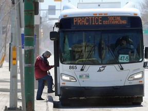A woman boards a Winnipeg Transit bus with the driver wearing a protective mask on Main Street on Wed., April 29, 2020.