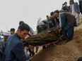 Mourners carry a covered body during a burial ceremony following a suicide attack in a maternity hospital, at a cemetery in Kabul on May 13, 2020.