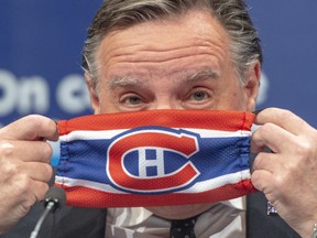Quebec Premier Francois Legault puts on a Montreal Canadiens face mask as he finishes the daily COVID-19 press briefing, Thursday, May 21, 2020 in Montreal.