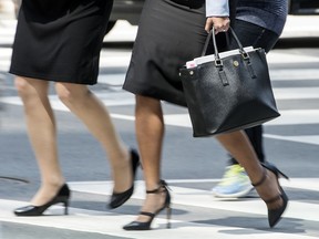 A businesswoman walks with her briefcase in Toronto's Financial District, Wednesday May 23, 2018.