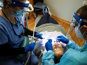 Dentists preform an oral procedure.