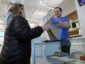 A customer is handed her purchase from behind a plexiglass screen at the Delta 9 cannabis store on Dakota Street in St. Vital on Mon., March 23, 2020.