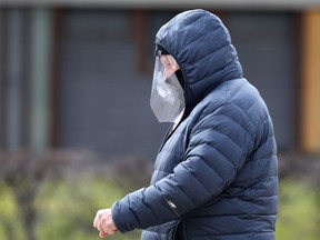 A man walks along Corydon Avenue, in Winnipeg, while wearing a face shield on Sunday.