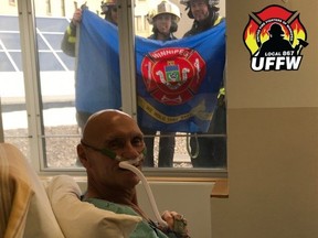Rick Sterzer, a 65-year-old retired firefighter, sits in his hospital bed as Winnipeg firefighters stand outside his window in this handout photo which was posted to the United Fire Fighters of Winnipeg Local 867 Twitter page on April 11.