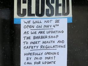 A sign on the glass door of Jeffrey's Barber Shop on Maryland Street in Winnipeg on Sunday.