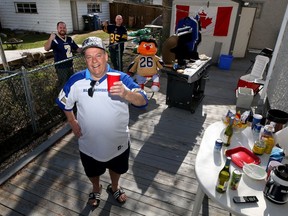 Daryl Budnick (centre), who is planning a virtual tailgate party on the day the CFL season was to open, does the neighbourly thing with Michael Murray (left) and Marcel Gauthier at his home in Winnipeg.
