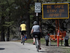 Electronic signs promoting social distancing measures in the wake of COVID-19 greet people arriving at St. Vital Park in Winnipeg on Monday.