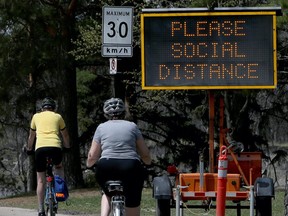 Electronic signs promoting social distancing measures in the wake of COVID-19 greet people arriving at St. Vital Park in Winnipeg on Mon., May 18, 2020.