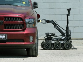The Winnipeg police bomb squad robot removes a glove from the gas tank area of a vehicle at the Murray Auto Group location on Pembina Highway in Winnipeg on Wed., May 20, 2020. Kevin King/Winnipeg Sun/Postmedia Network