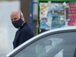 A man walks along Sargent Avenue while wearing a mask.