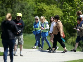 Social distancing ambassadors mingle with people near Assiniboine Park on Saturday.
