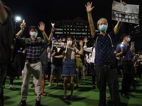 People gesture the popular protest slogan 'Five demands, not one less' as they attend a vigil in Victoria Park in Hong Kong on June 4, 2020, after the annual remembrance that traditionally takes place in the park to mark the 1989 Tiananmen Square crackdown was banned on public health grounds because of the COVID-19 coronavirus pandemic.
