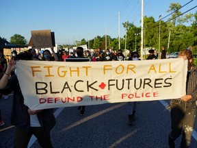 Protesters carry a banner calling to defund the police during a protest against police brutality in Florissant, Missouri, June 10, 2020.