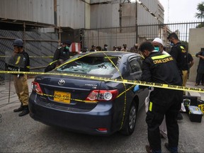 Members of the Crime Scene Unit investigate a car used by alleged gunmen at the main entrance of the Pakistan Stock Exchange building in Karachi on June 29, 2020.