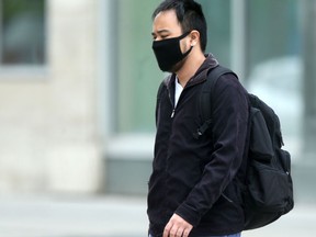 A man wearing a mask walks along Portage Avenue, in downtown Winnipeg on Tuesday.