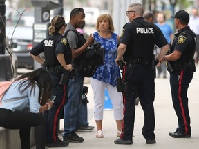 Police officers intervene during a dispute between a black man and a bank manager on Portage Avenue in Winnipeg on Monday. The man could be heard taking issue with the way the bank treats people of colour.
