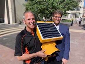 Chuck Lewis of Expert Electrical poses with Coun. Kevin Klein (Charleswood-Tuxedo-Westwood), with one of the solar-powered school zone lights at a City Hall in Winnipeg on Friday.