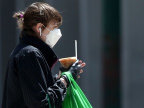 A woman wears a mask and one glove while walking along Portage Avenue on Saturday.