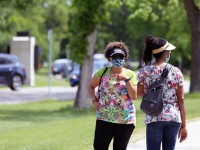 Two women wearing masks chat in Assiniboine Park in Winnipeg on Sunday.
