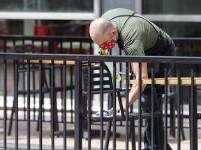 A chair is disinfected on the patio for King + Bannatyne, Bronuts, and Chosabi in the Exchange District in Winnipeg on Tuesday. Restaurants are among the hardest hit with those open earning 7% of the revenue they'd normally have at this time of year.