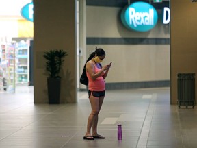 A woman wearing a mask checks her phone inside a barren Cityplace in Winnipeg on Wed., June 17, 2020. Kevin King/Winnipeg Sun/Postmedia Network
