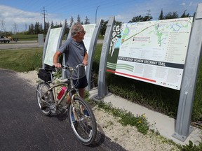 A cyclist consults a map for the Bishop Grandin Greenway Trail off Bishop Grandin Boulevard at River Road in the St. Vital area of Winnipeg on Tues., June 23, 2020. The city wants a committee to consider to consider historical markers. Kevin King/Winnipeg Sun/Postmedia Network