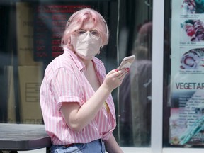 A woman wearing a mask sits outside a restaurant on Corydon Avenue in Winnipeg on Tuesday, June 30, 2020. Kevin King/Winnipeg Sun/Postmedia Network