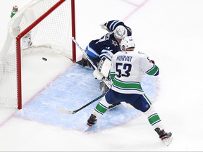 Jets goalie Connor Hellebuyck makes a save during the third period against the Vancouver Canucks in an exhibition game prior to the 2020 NHL Stanley Cup playoffs at Rogers Place in Edmonton on Wednesday night.