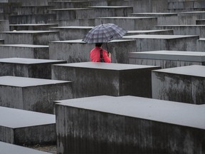 A woman with an umbrella walks during a rainy day at Holocaust Memorial in Berlin.